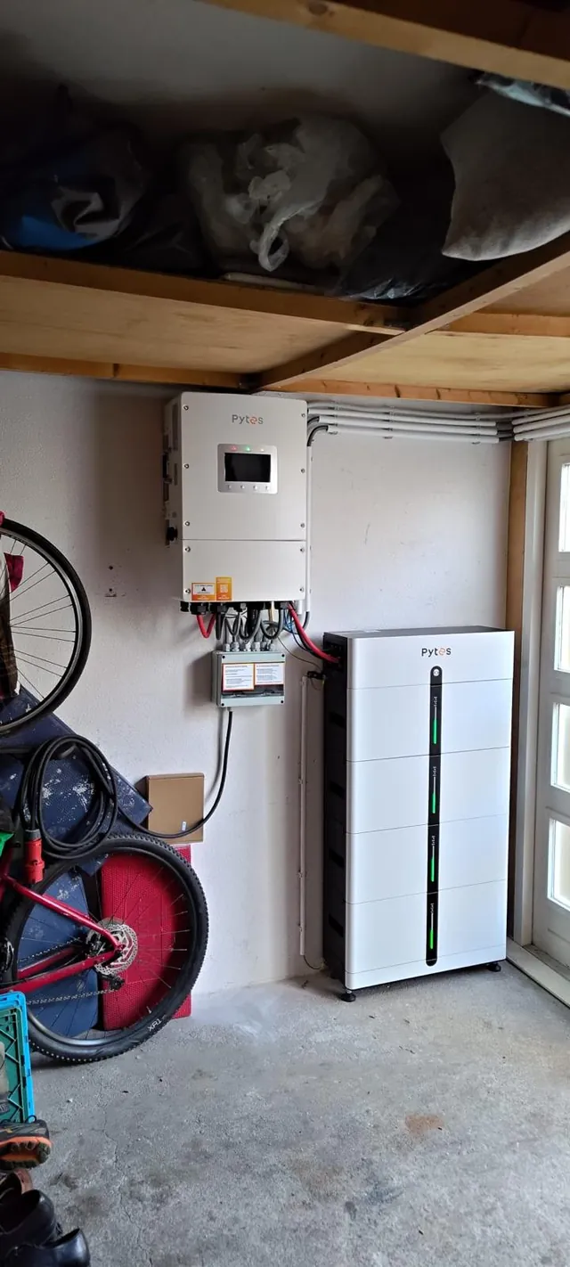Echte compacte thuisbatterij-installatie in een garage met fietsen en opbergruimte